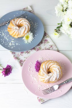 Beyaz masa, sonbahar kasımpatı pembe ve gri tabakta üzerine Hindistan cevizi cips ile lezzetli kek. Ailece kahvaltı. Metin, kopya alanı için boş alan.