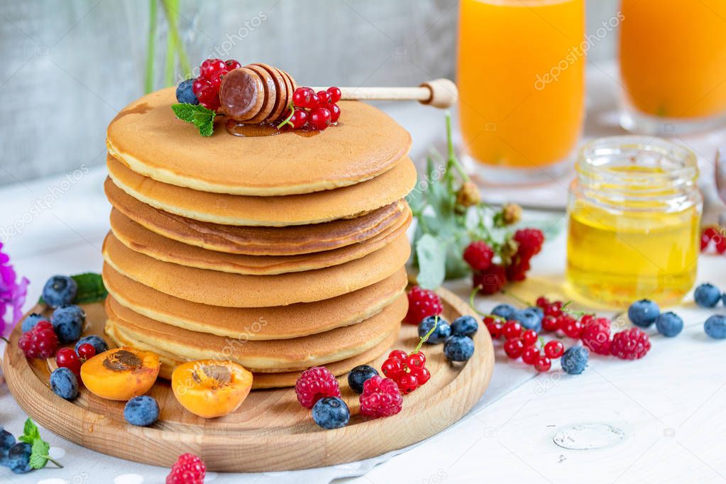 Fresh delicious pancakes with summer berries on light surface