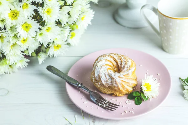 Leckere Kuchen mit Kokosraspeln auf rosa Teller auf weißem Tisch — Stockfoto