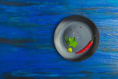 Ayrıca taze otlar, biber ve baharat ile koyu mavi ahşap yüzey üzerinde siyah seramik kaplama