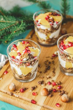 Ahşap kesme tahtası, mavi turkuaz ahşap masa, kopya sağlıklı tatil kahvaltıda granola, portakal ve nar meyve ile Yunan yoğurt uzay, sığ derinlik-in tarla.