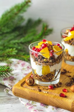 Ahşap kesme tahtası, mavi turkuaz ahşap masa, kopya sağlıklı tatil kahvaltıda granola, portakal ve nar meyve ile Yunan yoğurt uzay, sığ derinlik-in tarla.