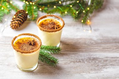 Noel ve kış tatillerinde tarçınlı yumurta likörü ve hindistan cevizi. Ahşap masa yüzeyinde gözlüklü ev yapımı eggnog, alanın sığ derinliği, kopyalama alanı.