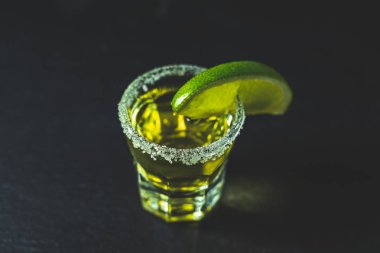 Meksika altın tekila kireç ile vurdu ve tuz siyah taş masa yüzeyi, seçici odak, sığ derinlik-in tarla, kopya alanı.