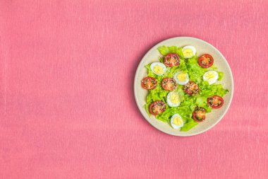 Taze sağlıklı salata marul, bıldırcın yumurtası, kiraz domates ve susam plaka ile. Üstten görünüm, kopya alanı, mercan tablo, yüzey yaşayan.