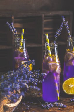 Taze menekşe kokteyl limon, buz ve lavanta, içki şişeleri camına bir karanlık eski rustik tarzı, seçici odak, sığ derinlik-in tarla.