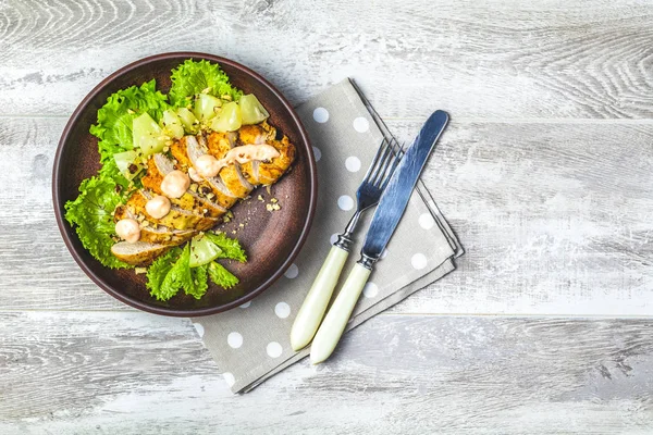 Delicious salad, chicken with pineapple, lettuce, cream sauce and walnut in ceramic plate on light gray wooden surface, top view, copy space, hawaiian, asian food