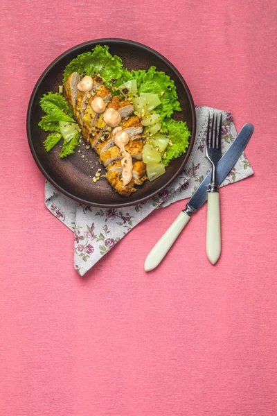 Delicious salad, chicken with pineapple, lettuce, cream sauce and walnut in ceramic plate on a  living coral table surface, top view, copy space, hawaiian, asian food