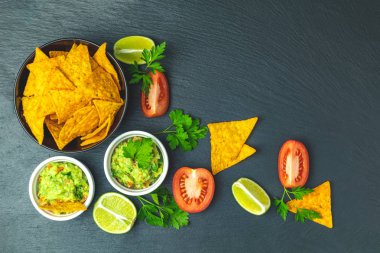 Guacamole ve cips malzemelerin üzerine siyah bir taş tahta arka plan ile. Üstten görünüm, kopya alanı.