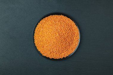 Kırmızı mercimek siyah plaka siyah taş üzerinde arka plan masa. Üstten görünüm, kopya alanı.