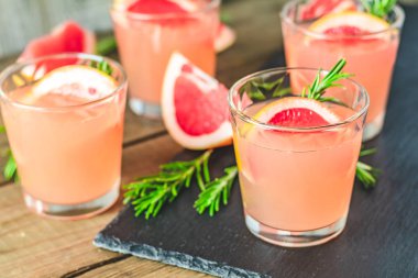 Greyfurt, buz ve biberiye, içki camına bir siyah taş masa, eski rustik tarzı, seçici odak, sığ derinlik-in tarla taze pembe alkollü kokteyl.