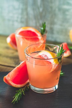 Greyfurt, buz ve biberiye, içki camına bir siyah taş masa, eski rustik tarzı, seçici odak, sığ derinlik-in tarla taze pembe alkollü kokteyl.