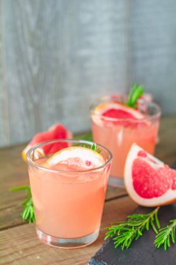 Greyfurt, buz ve biberiye, içki camına bir siyah taş masa, eski rustik tarzı, seçici odak, sığ derinlik-in tarla taze pembe alkollü kokteyl.