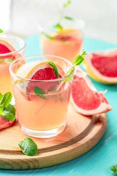 新鲜的粉红色酒精鸡尾酒 包括葡萄柚 冰和薄荷 饮料杯和成分在蓝色绿松石桌子上 选择性焦点 浅景深 — 图库照片