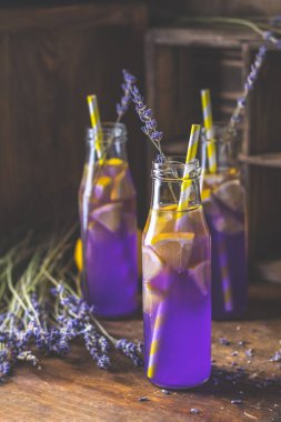 Taze lavanta menekşe kokteyl limon ve buz, içki şişeleri camına bir karanlık eski rustik tarzı, seçici odak, sığ derinlik-in tarla.