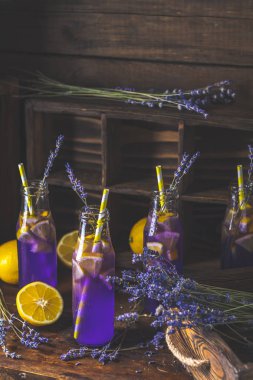 Taze lavanta menekşe kokteyl limon ve buz, içki şişeleri camına bir karanlık eski rustik tarzı, seçici odak, sığ derinlik-in tarla.
