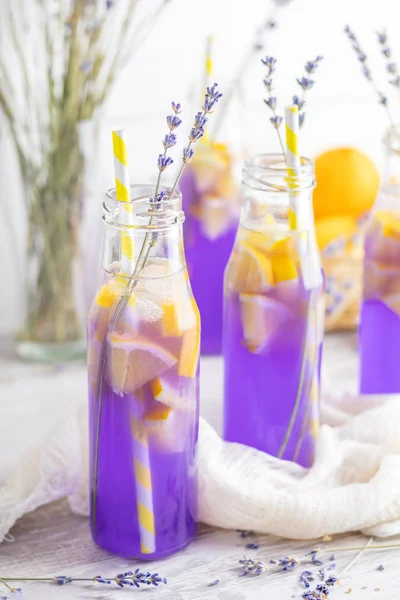 stock image Fresh lavender violet cocktail with lemon and ice, drink bottles glass on a  light old rustic style, selective focus, shallow depth of the field.