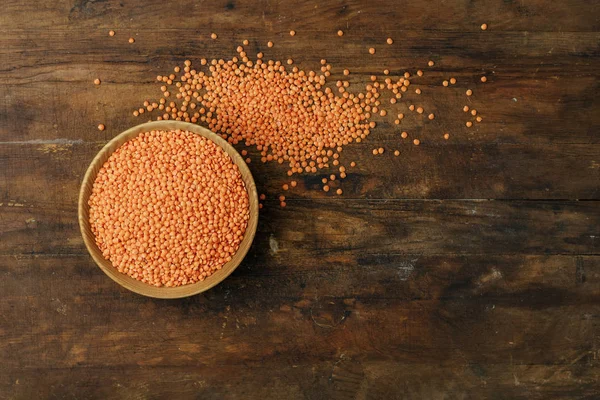 Ahşap plaka eski koyu ahşap masa arka plan üzerinde kırmızı mercimek. Üstten görünüm, kopya alanı.