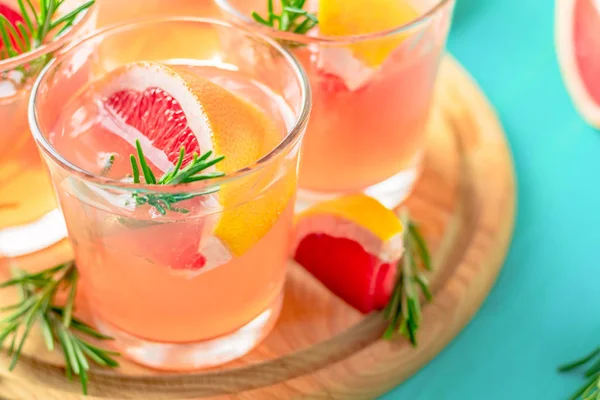 新鲜的粉红色酒精鸡尾酒 包括葡萄柚 冰和薄荷 饮料杯和成分在蓝色绿松石桌子上 选择性焦点 浅景深 — 图库照片