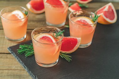 Greyfurt, buz ve biberiye, içki camına bir siyah taş masa, eski rustik tarzı, seçici odak, sığ derinlik-in tarla taze pembe alkollü kokteyl.