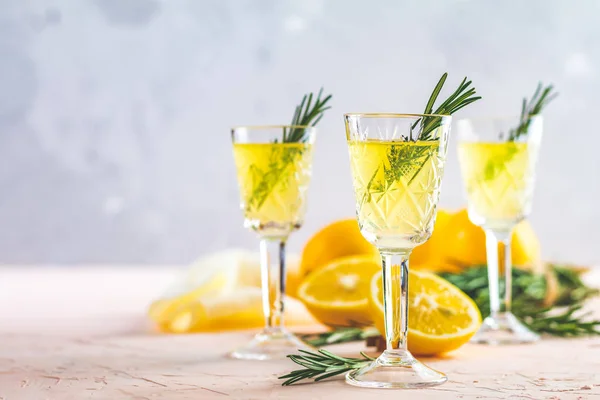 Geleneksel İtalyan ev yapımı limon alkol içki likör limoncello adet limon ve biberiye bitki hafif pembe mercan taş beton yüzeyine yaşayan üzerinde