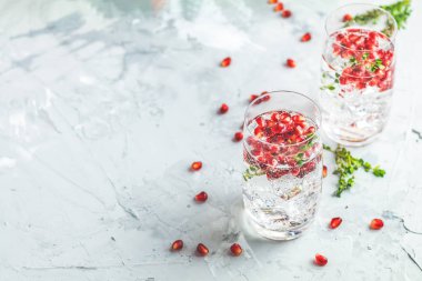 Festival içecekler, cin tonik nar kokteyl veya detoks su buz ile. Seçici odak, kopya alanı için metin, hafif gri beton masa yüzeyi.