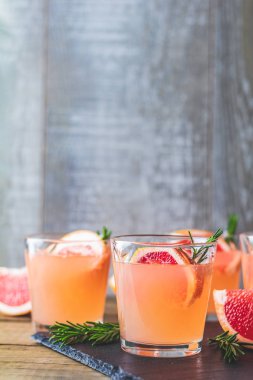 Greyfurt, buz ve biberiye, içki camına bir siyah taş masa, eski rustik tarzı, seçici odak, sığ derinlik-in tarla taze pembe alkollü kokteyl.