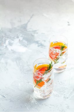 Greyfurt, soda, buz, cin ve biberiye, gri beton masa lambası arka plan, seçici odak, sığ derinlik-in tarla ile alkollü kokteyl.