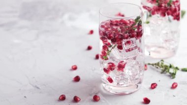 Festival içecekler, cin tonik nar kokteyl veya detoks su buz ile. Seçici odak, kopya alanı için metin, hafif gri beton masa yüzeyi.