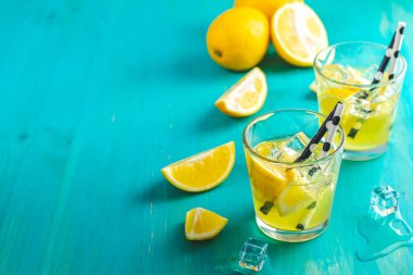 Limon alkol içki kokteyl buz, limon ve biberiye bitki mavi turkuaz ahşap masa arka plan yüzeyi ile. Geleneksel İtalyan ev yapımı limon alkol içki likör limoncello.