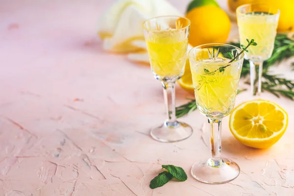Geleneksel İtalyan ev yapımı limon alkol içki likör limoncello adet limon ve biberiye bitki pembe üzerinde şeftali veya Mercan rengi taş beton yüzey