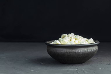 Ev yapımı peynir bir siyah seramik kase karanlık beton masa yüzeyi, kopya alanı.