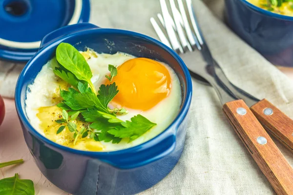 Yumurta kokot cocotte Fransız kahvaltı. Mavi seramik kalıpları pişirme pişmiş yumurtalar. Alakart Güveç sebze ve yumurta İtalyan tarzı.
