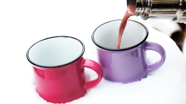 倒杯热巧克力 棉花糖在舒适冬季粉色围巾雪覆盖在花园里桌子上的粉红色和紫色两杯热巧克力 — 图库视频影像