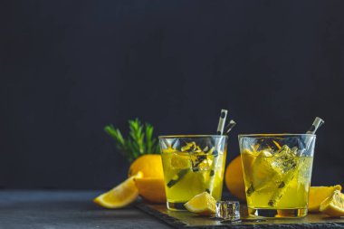 Limon alkol siyah taş beton yüzeyinde buz, limon ve biberiye bitki ile kokteyl içmek. Geleneksel İtalyan ev yapımı limon alkol içki likör limoncello.