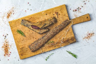 Sarsıntılı, basturma, kurutulmuş Dana eti, et eti baharat ahşap kesme tahtası, üstten görünüm, gri beton yüzey masa lambası arka plan ile füme.