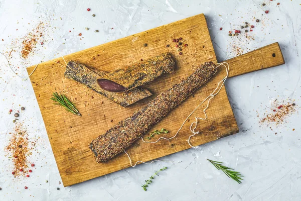 Sarsıntılı, basturma, kurutulmuş Dana eti, et eti baharat ahşap kesme tahtası, üstten görünüm, gri beton yüzey masa lambası arka plan ile füme.