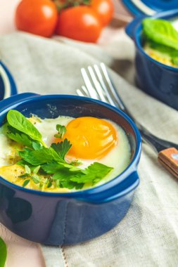 Yumurta kokot cocotte Fransız kahvaltı. Mavi seramik kalıpları pişirme pişmiş yumurtalar. Alakart Güveç sebze ve yumurta İtalyan tarzı.