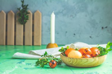 Bıldırcın yumurtası ve yeşil dallar Yeşil Beton yüzey arka plan üzerinde ahşap plaka ile renkli sarı turuncu yumurtalı paskalya tebrik kartı. Uzay kopyalayın. Tonlu görüntü