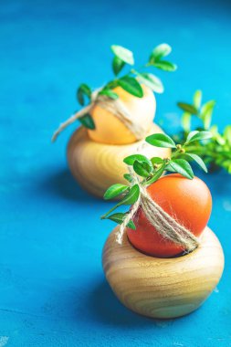 Paskalya tebrik kartı renkli sarı turuncu yumurta ile ahşap plaka yeşil dallar üzerinde mavi Beton yüzey arka plan dekore edilmiş. Uzay kopyalayın. Tonlu görüntü