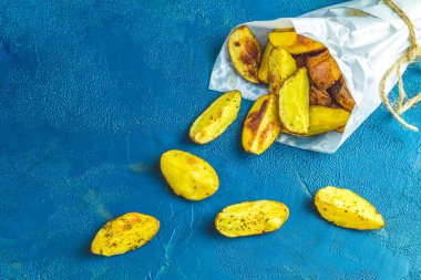 Fırında patates dilimleri kağıt üzerinde koyu mavi beton zemin üzerine yanı sıra deniz tuzu ile