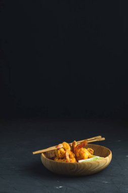 Kızarmış karides tempura kireç karanlık Beton yüzey zemin üzerine ahşap plaka ile. Sen metin için yer kopyalayın. Deniz ürünleri tempura çanak Japon ya da Doğu Asya tarzı çubuklarla.