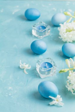 Paskalya yumurtaları, mumlar ve mavi beton tablo yüzey arka plan, sizin metin için kopya yer üzerinde beyaz sümbül mavi. Festival arka plan. Mutlu Paskalya tebrik kartı.