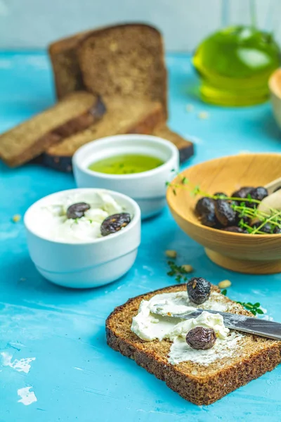Smetanový sýr na chleba přikrýval a sušené olivy — Stock fotografie