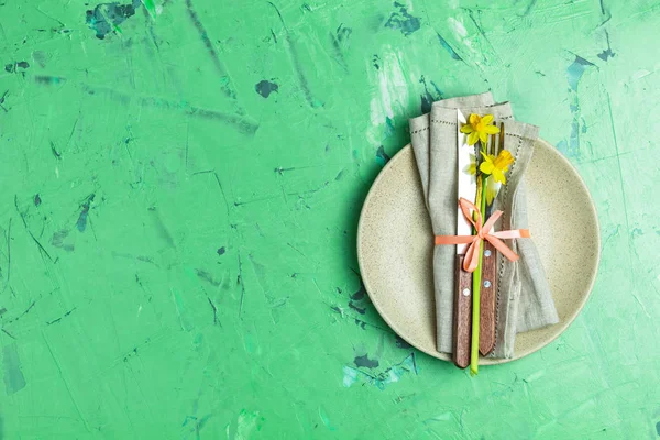Empty beige plate and cutlery with daffodils on a napkin — Stock Photo, Image