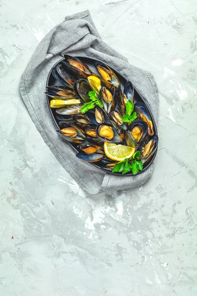 Zeevruchten mosselen met citroen en peterselie in zwarte metalen plaat — Stockfoto