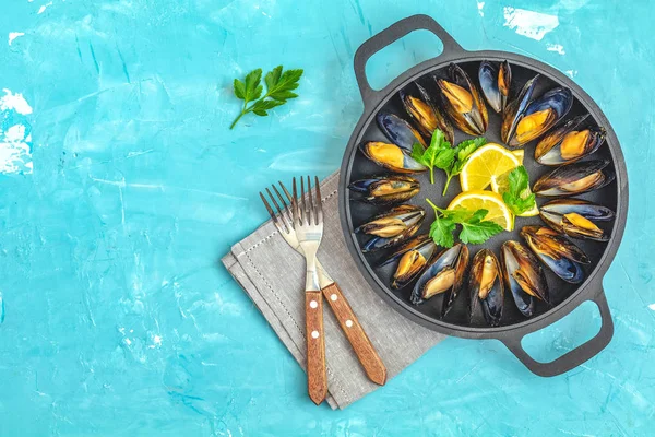 Zeevruchten mosselen met citroen en peterselie in zwarte metaalpan — Stockfoto