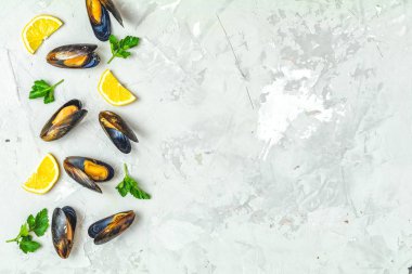 Gri beton yüzeyde deniz ürünleri midye, limon ve maydanoz