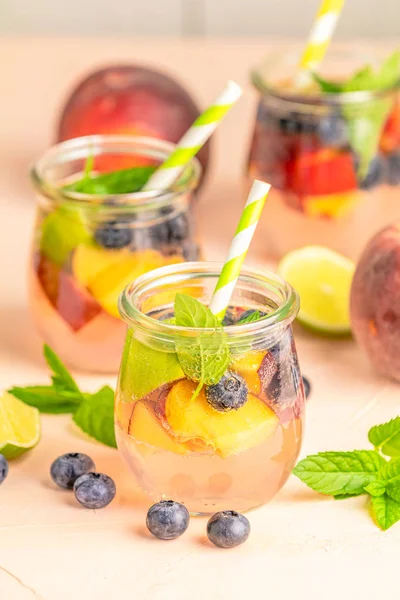 Blaubeeren und Pfirsiche enthalten Wasser, Cocktail, Limonade oder Tee. su — Stockfoto