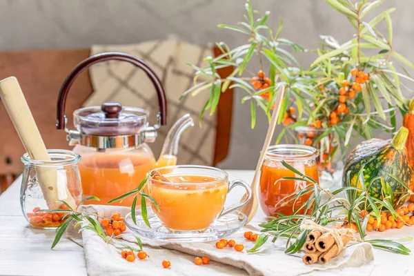 Hot spicy tea with sea buckthorn in glass cup and teapot, select